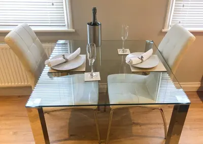 a glass table with white chairs and napkins on it at Luxury Apartment with king-size Bed in Central Cambridge - easy walk to Station and City Centre in Cambridge