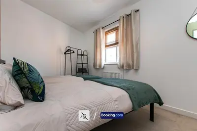 a bedroom with a bed with a green blanket on it at Stylish House By AR Properties Short Lets & Serviced Accommodation Colchester in Colchester