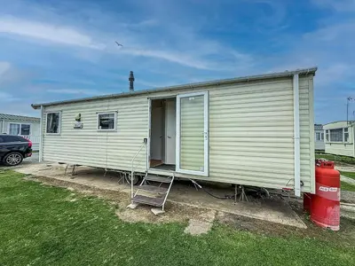 a mobile home with a ladder and a red container at Lovely 6 Berth Caravan At Seawick Holiday Park In Essex Ref 27008S in Clacton-on-Sea
