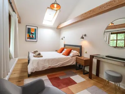 a bedroom with a bed and a desk and a mirror at The Cart Lodge at Grove Barn in Eye