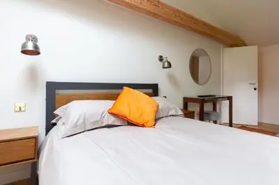 a bedroom with a white bed with an orange pillow at The Cart Lodge at Grove Barn in Eye