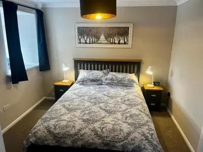a bedroom with a bed with two night stands and two lamps at Comfy, modern one bed apartment in Leiston