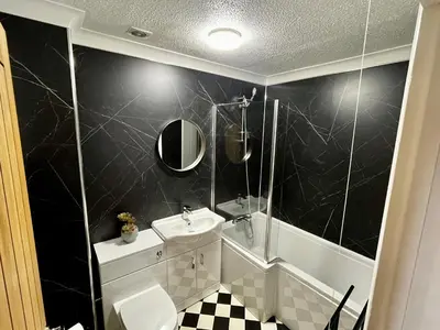 a bathroom with a sink and a toilet and a tub at Comfy, modern one bed apartment in Leiston