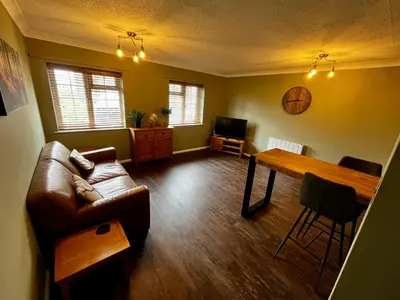 a living room with a couch and a table at Comfy, modern one bed apartment in Leiston