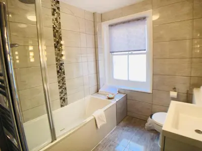 a bathroom with a tub and a toilet and a window at Ilfracombe House Hotel - near Cliffs Pavilion in Southend-on-Sea