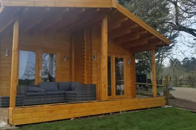 a log cabin with a couch in the grass at Bishy Barnabees country lodge with hot tub in Swaffham