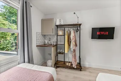 a bedroom with a bed and a shelf with clothes at The Suffolk Gem - Games Room in Ipswich