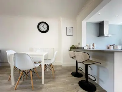 a kitchen with a table and chairs and a clock on the wall at Grace's Place in Ely in Ely