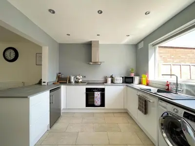 a kitchen with white cabinets and a washer and dryer at Grace's Place in Ely in Ely