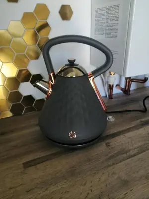 a black tea kettle sitting on a wooden table at The Cabin in Pakenham