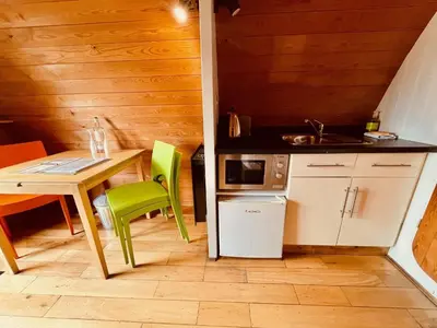 a small kitchen with a table and green chairs at MegaPod 1 at Lee Wick Farm Cottages & Glamping in Clacton-on-Sea