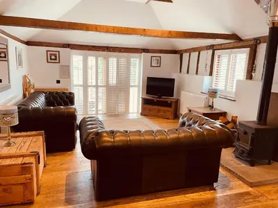 a living room with leather couches and a television at Stable Cottage at Lee Wick Farm Cottages & Glamping in Clacton-on-Sea