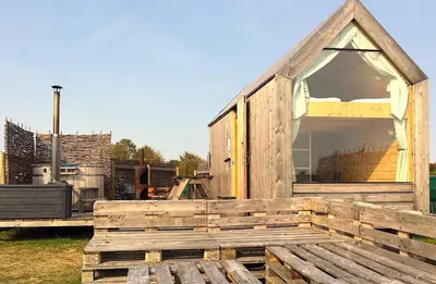 a wooden house with a large window on the deck at Lushna 4 Petite at Lee Wick Farm Cottages & Glamping in Clacton-on-Sea