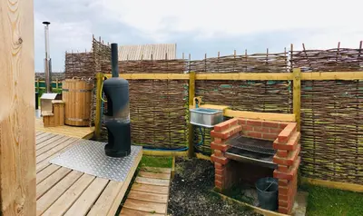 a patio with a brick oven on a deck at Lushna 7 Petite at Lee Wick Farm Cottages & Glamping in Clacton-on-Sea