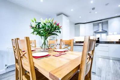 a dining room table with chairs and a vase of flowers at leigh Penthouse Apartment in Leigh-on-Sea