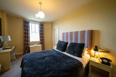 a bedroom with a large bed with a blue blanket at Milsoms in Dedham