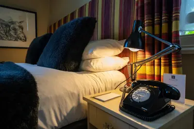 a hotel room with a bed and a desk with a telephone at Milsoms in Dedham