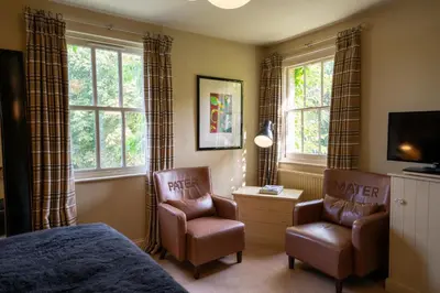 a bedroom with a bed and a chair and a tv at Milsoms in Dedham