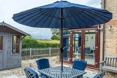 a table and chairs with an umbrella on a patio at 2 Bedroom Rural Escape In Peaceful Elmswell in Woolpit