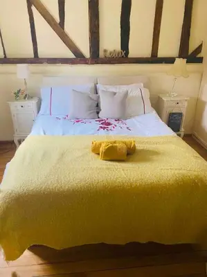 a bed with a yellow blanket on top of it at Stunning barn conversion ideal for large families in Bildeston