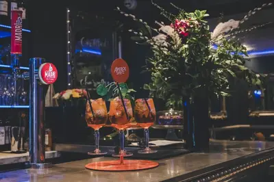 two glasses on a bar with a vase of flowers at Camelia Hotel in Southend-on-Sea