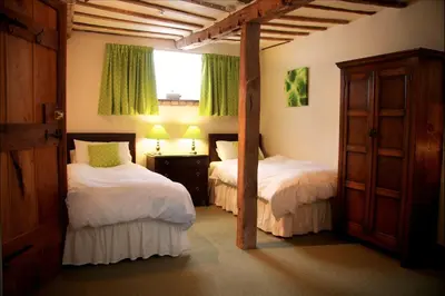 a bedroom with two beds and a window with green curtains at Colston Hall Farmhouse B&B in Framlingham