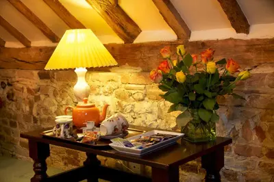 a table with a lamp and a vase of flowers at Colston Hall Farmhouse B&B in Framlingham