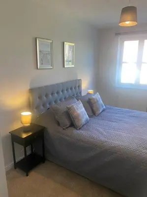 a bedroom with a bed with two pillows and a table at Colchester Smart Two Bed Apartment in Colchester