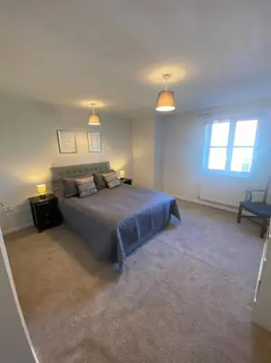 a bedroom with a bed and two lamps and a window at Colchester Smart Two Bed Apartment in Colchester