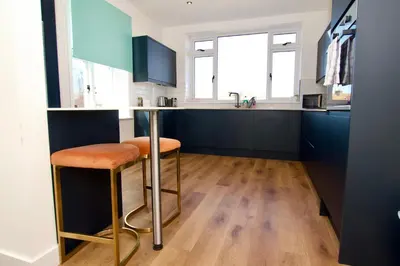 a kitchen with a bar with two stools at Beautiful large 3-bed coastal flat with parking. in Frinton-on-Sea