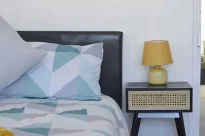 a bed with a side table with a lamp on it at Beautiful large 3-bed coastal flat with parking. in Frinton-on-Sea