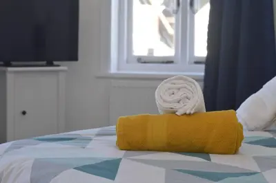 a yellow towel on top of a bed at Beautiful large 3-bed coastal flat with parking. in Frinton-on-Sea