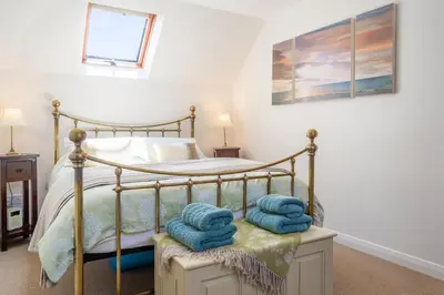a bedroom with a bed with towels on a stool at Escape in Aldeburgh