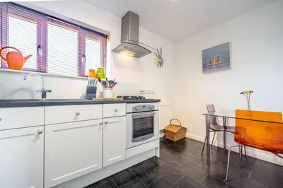 a kitchen with white cabinets and a glass table at Escape in Aldeburgh