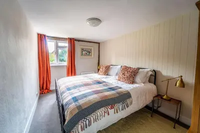 a bedroom with a bed and a window with orange curtains at 5 Bed Farmhouse Suitable for Contractors Private Parking in Potter Street