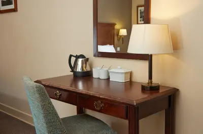 a desk in a hotel room with a lamp and a mirror at Bell by Greene King Inns in Thetford