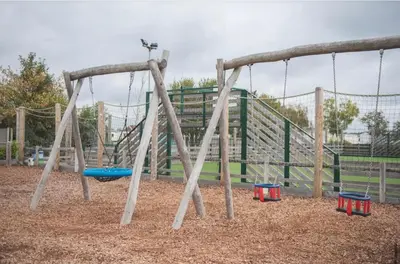 a playground with a swing set in a park at Brand New Modern Holiday Home - Haven The Orchards Holiday Park in Saint Osyth