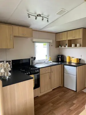 a kitchen with wooden cabinets and black counter tops at Lovely place in Saint Osyth