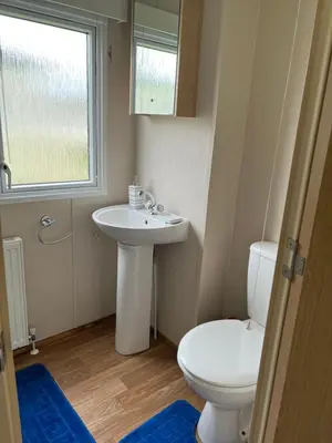 a bathroom with a toilet and a sink and a window at Lovely place in Saint Osyth