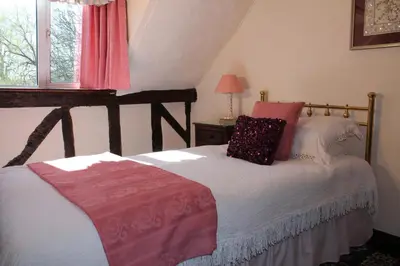 a bedroom with a wooden bed with pillows on it at Colston Hall Cottages in Framlingham