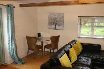 a living room with a couch and a table at The Lodge - 2 acres of garden with hot tub and fire pit and BBQ in East Harling
