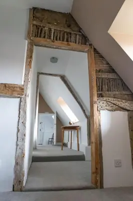 an attic room with a staircase and a table at The Thatched Flat at The Sorrel Horse in Shottisham