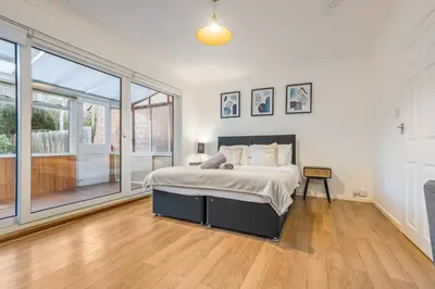 a bedroom with a bed and a large window at Comfortable 4-BDR House, Sleeps 7, WIFI, Secure Parking in Cambridge