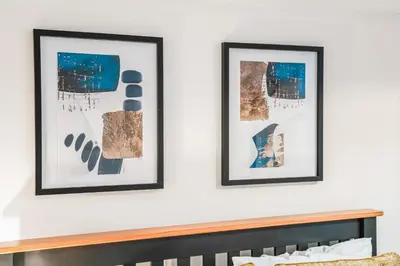 two framed pictures on a white wall above a bed at Comfortable 4-BDR House, Sleeps 7, WIFI, Secure Parking in Cambridge