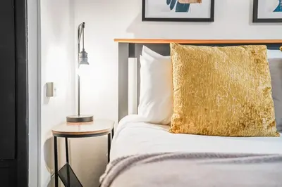 a bed with a gold pillow and a side table at Comfortable 4-BDR House, Sleeps 7, WIFI, Secure Parking in Cambridge