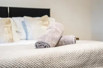 a rolled up towel on top of a bed at Comfortable 4-BDR House, Sleeps 7, WIFI, Secure Parking in Cambridge