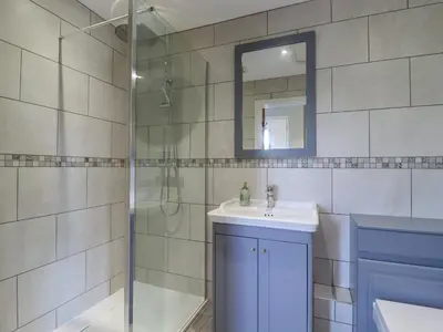 a bathroom with a shower and a sink and a mirror at Pippin Cottage in Clacton-on-Sea