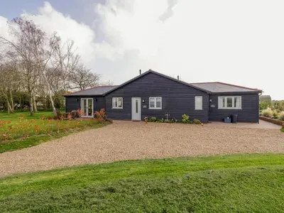 a black house with a gravel driveway at Pippin Cottage in Clacton-on-Sea