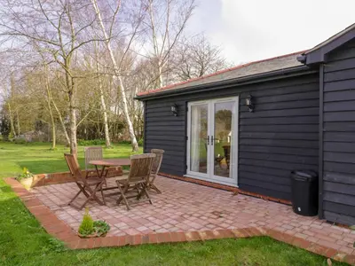 a patio with a table and chairs next to a house at Bramley Cottage in Clacton-on-Sea