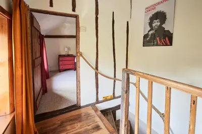 a hallway with a staircase and a poster on the wall at Church Cottage in Halesworth